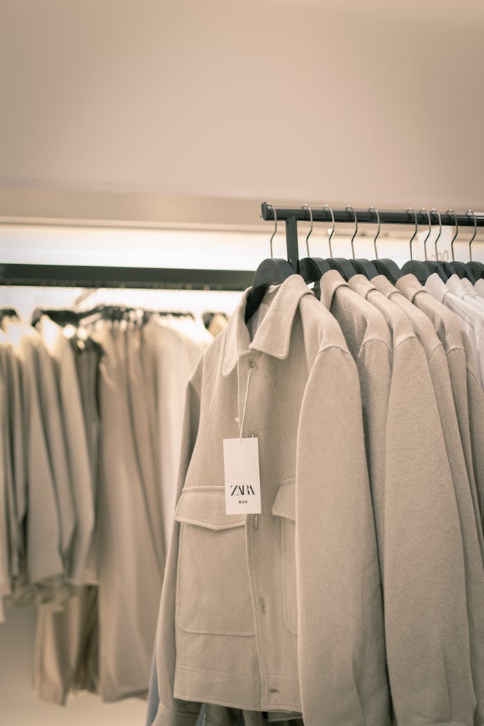 Home Stylish beige coats neatly arranged on racks in a modern clothing store interior.