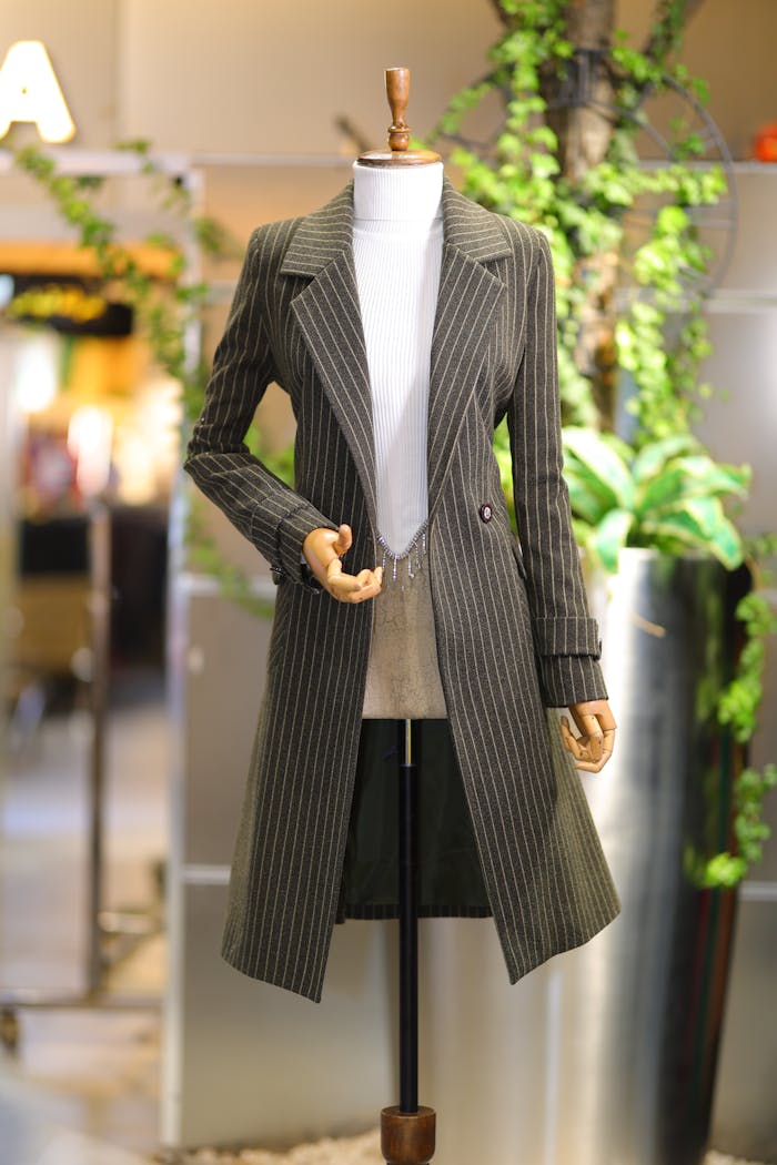 Elegant striped coat displayed on a mannequin in a retail store setting.